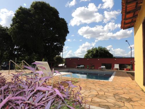 une piscine avec des plantes violettes en face d'un bâtiment dans l'établissement Pousada Caminho Dos Sinos, à Tiradentes