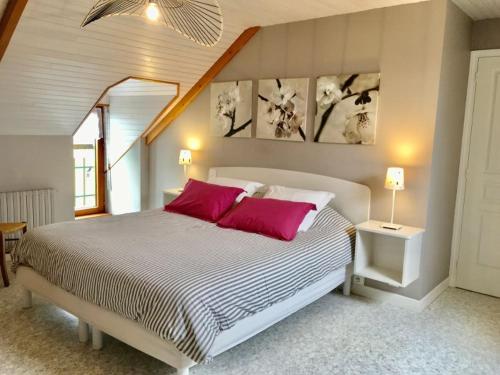 Un dormitorio con una cama grande con almohadas rojas. en Gite, en Saint-Denoual