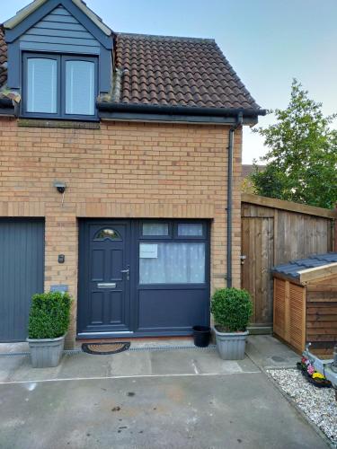 a brick house with a black garage door at Riverwood Retreat - Self Contained Lux Apartment, Close to the Celtic Resort in Kemeys Inferior