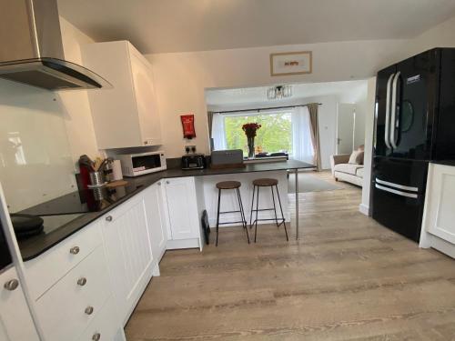 een keuken met witte kasten en een zwarte koelkast bij Port Side Brixham - Ideal seaside getaway - parking - wood-burner - dog friendly in Brixham