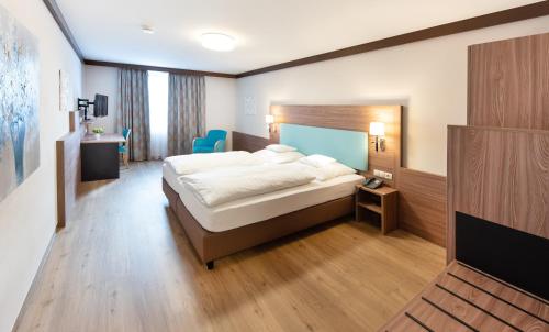 una habitación de hotel con una cama y un televisor en Hotel Gumberger GmbH Garni, en Neufahrn bei Freising
