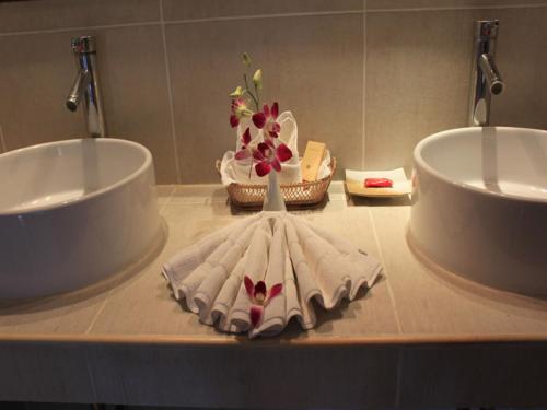 een badkamerbar met 2 wastafels en een vaas met bloemen bij The Waterfront Hotel at Fishermans Village in Bophut 