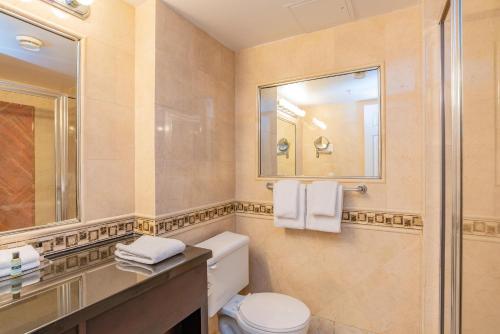 a bathroom with a toilet and a sink and a mirror at Sandman Hotel Vancouver Airport in Richmond