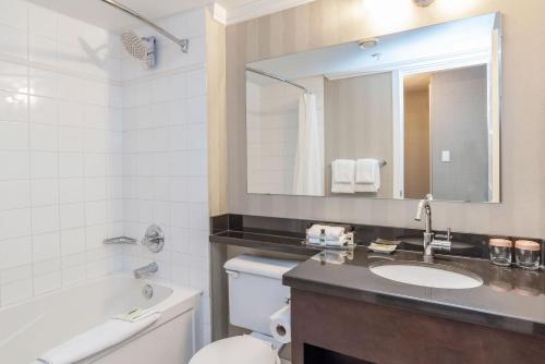 a bathroom with a sink and a toilet and a mirror at Sandman Hotel Vancouver Airport in Richmond