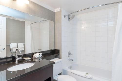a bathroom with a sink and a toilet and a tub at Sandman Hotel Vancouver Airport in Richmond