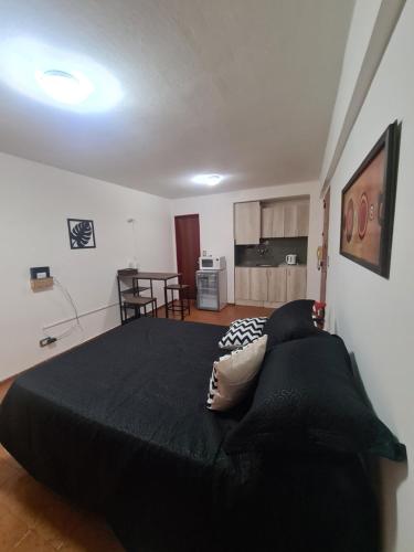 a bedroom with a large black bed and a kitchen at Hermoso Monoambiente en Nva Cordoba in Córdoba