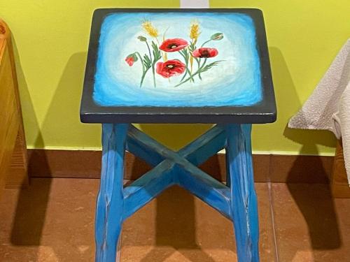 a painting of red flowers on a blue stool at Agroturystyka Hanka i Jurek in Boruja