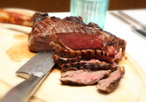 a steak on a cutting board next to a knife at Berghotel Hois in Heiligenblut