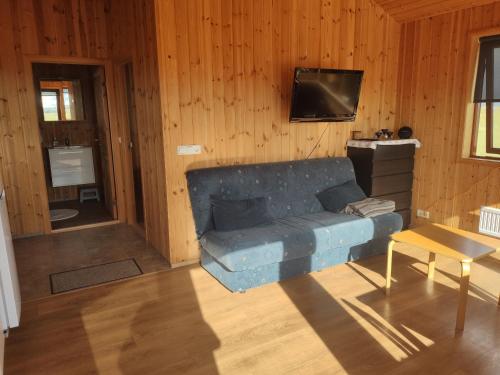 a living room with a blue couch and a television at Bright and Peaceful Cabin with Views & Hot Tub in Selfoss