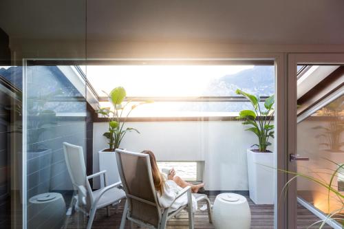 a person sitting in a chair on a balcony at Hotel Lago Di Garda in Nago-Torbole