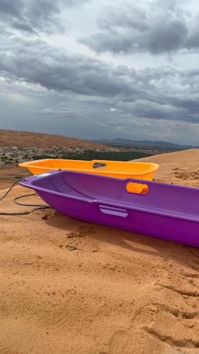 a purple and orange boat sitting on the sand at شاليهات رمال بديه in Al Raka