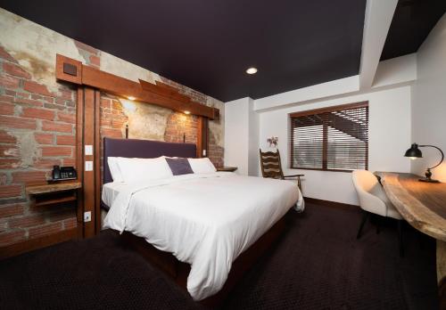 a bedroom with a large white bed and a brick wall at The Horton Hotel in Boone