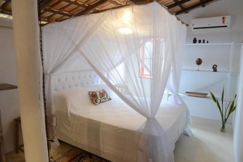 Casa Alegre Trancoso, piscina, 3 suítes e ar-cond. في ترانكوسو: سرير أبيض مع ستارة في الغرفة