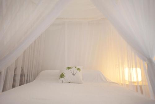a white bed with a pillow and two plants on it at Casa Alegre Trancoso, piscina, 3 suítes e ar-cond. in Trancoso