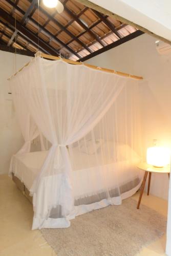 a bedroom with a bed with white mosquito netting at Casa Alegre Trancoso, piscina, 3 suítes e ar-cond. in Trancoso