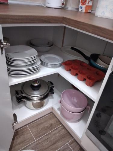 a kitchen cabinet with plates and pans and dishes at Apartman Cer in Banja Koviljača