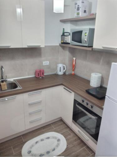 a kitchen with white cabinets and a sink and a microwave at Apartman Cer in Banja Koviljača