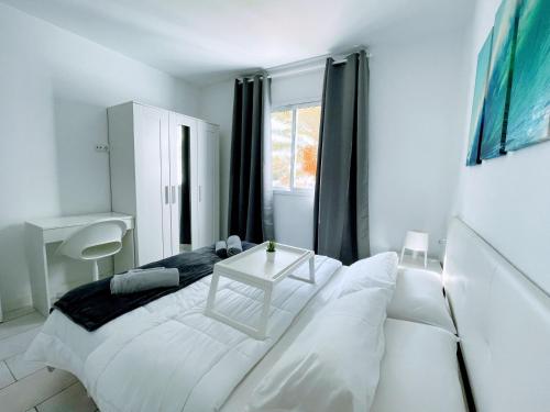 コラレホにあるSinfonia Corralejo iRent Fuerteventuraの白いベッドルーム(ベッド1台、テーブル付)