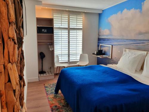 a bedroom with a blue bed and a window at Badhotel Bruin in Oost-Vlieland