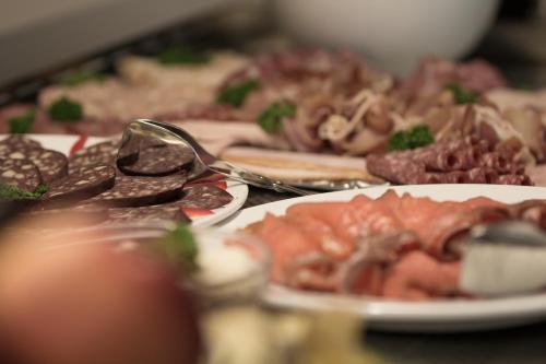 a table topped with plates of meat and other foods at Hotel Müritzterrasse in Röbel