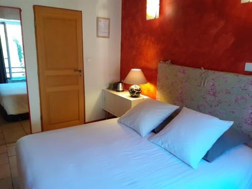 a bedroom with a white bed with a red wall at Au coeur du Caylar in Le Caylar