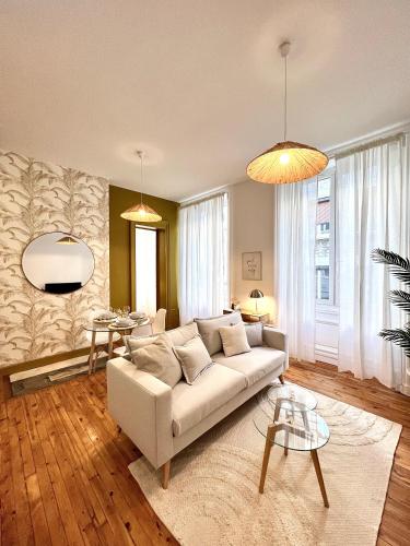 uma sala de estar com um sofá branco e uma mesa em La plume dorée - Hotel de ville em Saint Etienne