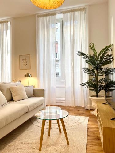 a living room with a couch and a table at La plume dorée - Hotel de ville in Saint Etienne