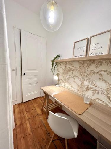 a desk with a white chair in a room at La plume dorée - Hotel de ville in Saint Etienne
