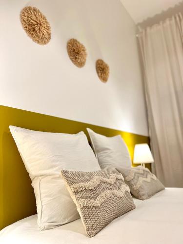 a bed with white pillows and hearts on the wall at La plume dorée - Hotel de ville in Saint Etienne