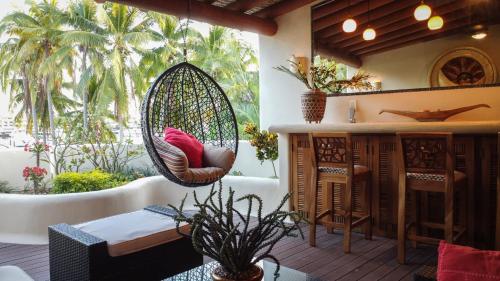 a patio with a hanging swing and a table and chairs at Villa Marina Ixtapa in Ixtapa