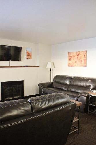 a living room with black leather furniture and a fireplace at Bowen Motel in Moab