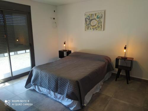 een slaapkamer met een bed en twee nachtkastjes met lampen bij FLOR DE LAVANDA in Santa Rosa de Calamuchita