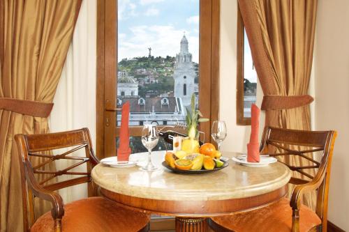 Plaza Grande Hotel في كيتو: طاولة مع صحن من الفاكهة وإطلالة على المدينة