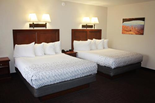 two beds in a hotel room with white sheets at Bowen Motel in Moab
