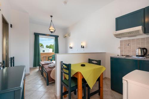 a kitchen with a yellow table and chairs in a kitchen at Cirillo Family Hotel-Christinas Studios in Mastichari