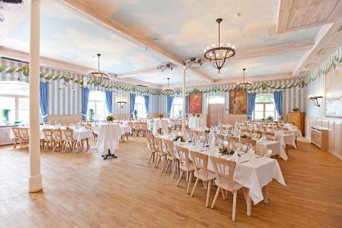 Un salón de banquetes con mesas y sillas blancas. en DIE POST Landgasthof Aufkirchen, en Berg am Starnberger See