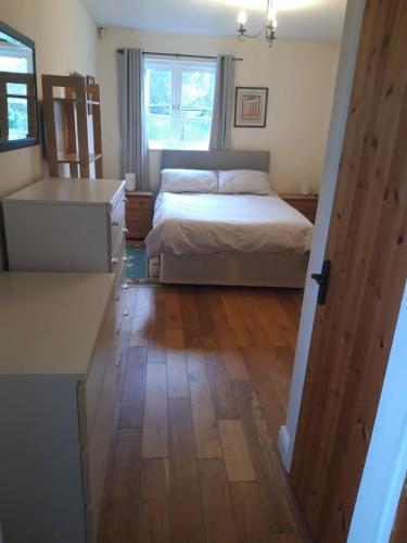 a bedroom with a bed and a wooden floor at Little Orchard Cottage in Canterbury