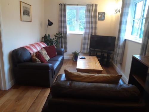 a living room with a couch and a coffee table at Little Orchard Cottage in Canterbury