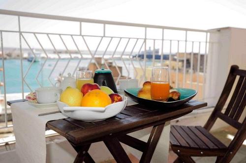 a table with a bowl of fruit and a glass of juice at A Babordo B&B in Trapani