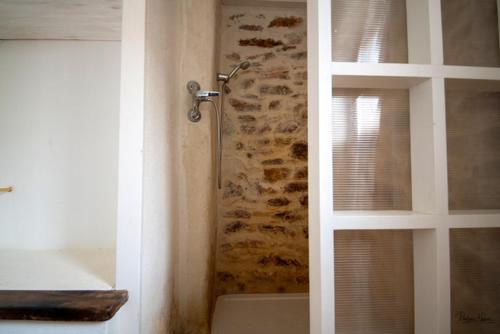 La salle de bains est pourvue d'une douche et d'un mur en pierre. dans l'établissement Maison charmante à Faugères avec vue sur la montagne, à Faugères