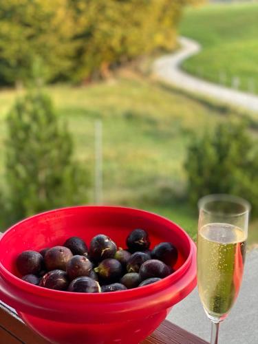 a red bowl of olives next to a glass of wine at Farmhouse Lipoglav in Loče pri Poljčanah