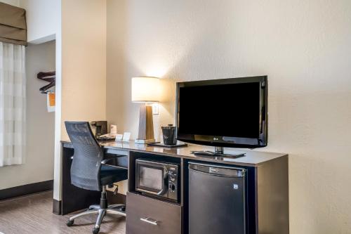 a hotel room with a desk with a television and a chair at Sleep Inn & Suites Jacksonville near Camp Lejeune in Jacksonville