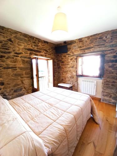 a bedroom with a large bed in a stone wall at Casa Carmelo in Viveiro