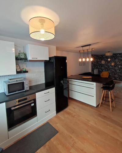 une cuisine avec des armoires blanches et un réfrigérateur noir dans l'établissement Le filet Cherbourgeois, à Cherbourg en Cotentin