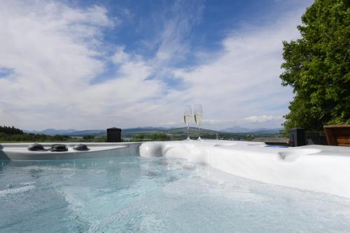 a swimming pool with a view of the mountains at Super King Lodge-Sleeps 2-HotTub-Sea View in Langbank