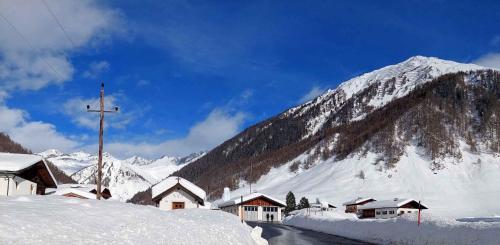 a snow covered mountain with houses and a cross on a road at Apartment in Schmirn - Tirol 717 in Schmirn
