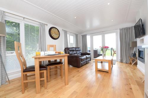a living room with a table and a chair at Super King Lodge-Sleeps 2-HotTub-Sea View in Langbank