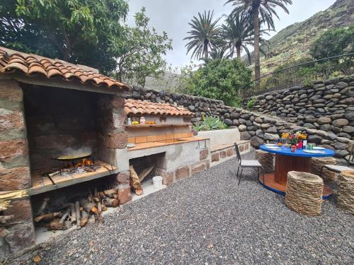 a stone patio with a table and a fireplace at Haciendita Gomera in San Sebastián de la Gomera