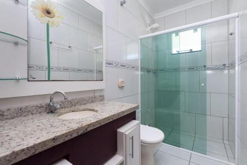 Un baño con lavabo y ducha de cristal. en CASA JACUÍ A 350 METROS DA PRAIA, en Bombinhas