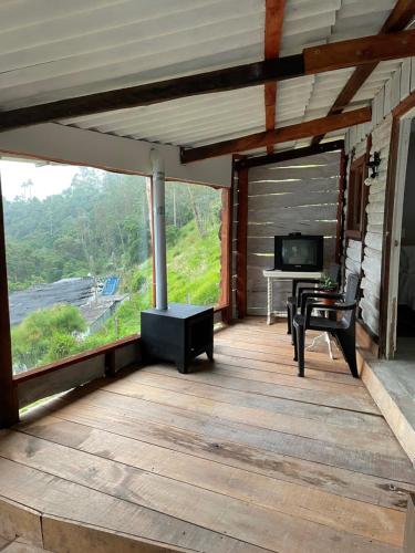 a screened in porch with a television and a desk at Cabañas Valle del Cocora La Truchera in Salento